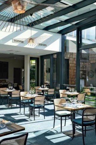 Terrasse extérieure du restaurant à l’Hôtel des Bains Thalazur avec tables et chaises au design moderne, créant un espace élégant et lumineux pour les convives.
