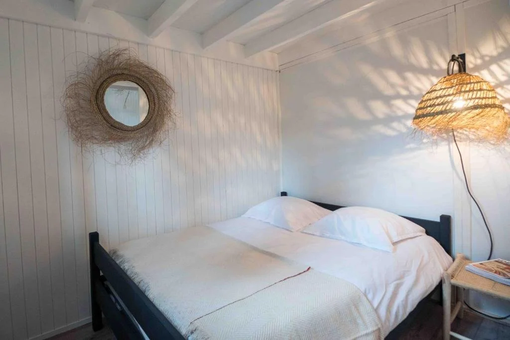 Habitación de cabaña en Slow Village Biscarrosse Lac con paredes de madera blanca y un diseño minimalista, creando un espacio tranquilo y acogedor para los huéspedes.
