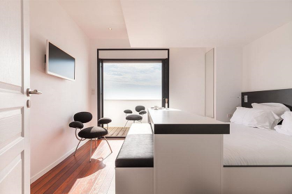 Chambre d’hôtel au Grand Hotel de la Plage avec un design minimaliste et de grandes fenêtres donnant directement sur la mer et la plage de Biscarrosse.