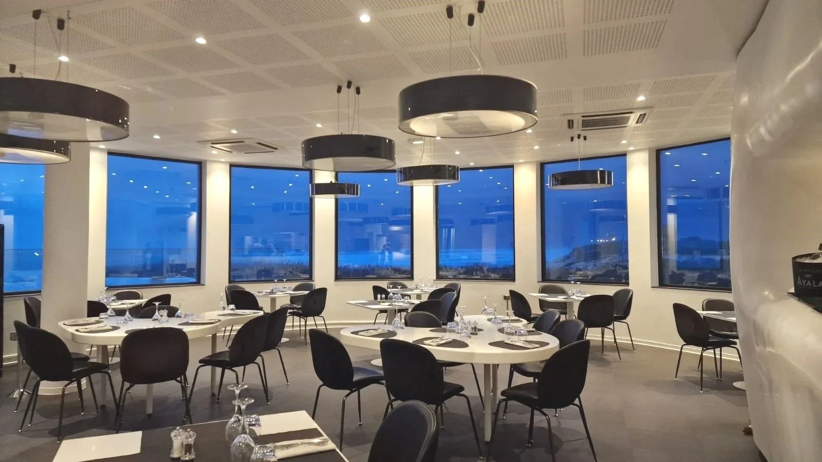 Salle circulaire avec grandes fenêtres au Grand Hôtel de la Plage, idéale pour des réunions ou des dîners avec vue panoramique sur l’océan. L’espace a une lumière naturelle.
