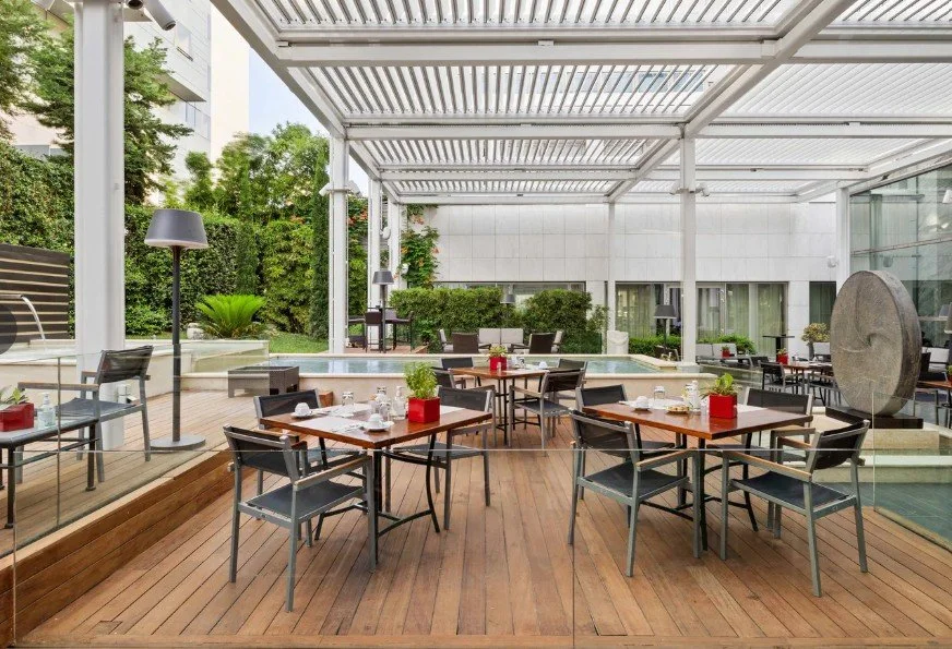 Terrasse extérieure de l’hôtel Marriott avec tables et pergola, un espace parfait pour les dîners de groupe et des événements sociaux.