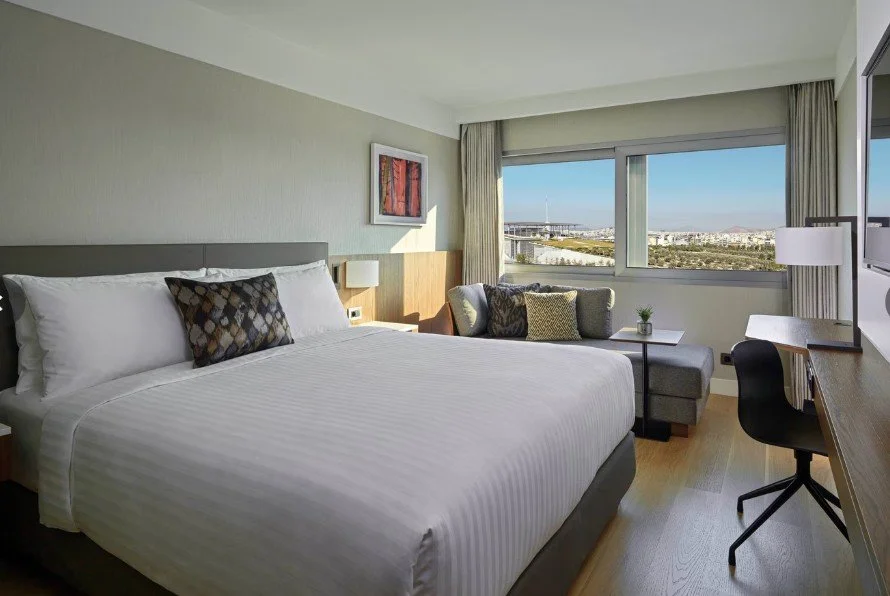 Chambre élégante et moderne de l’hôtel Marriott avec lit et bureau, idéale pour les voyages d’affaires à Athènes.