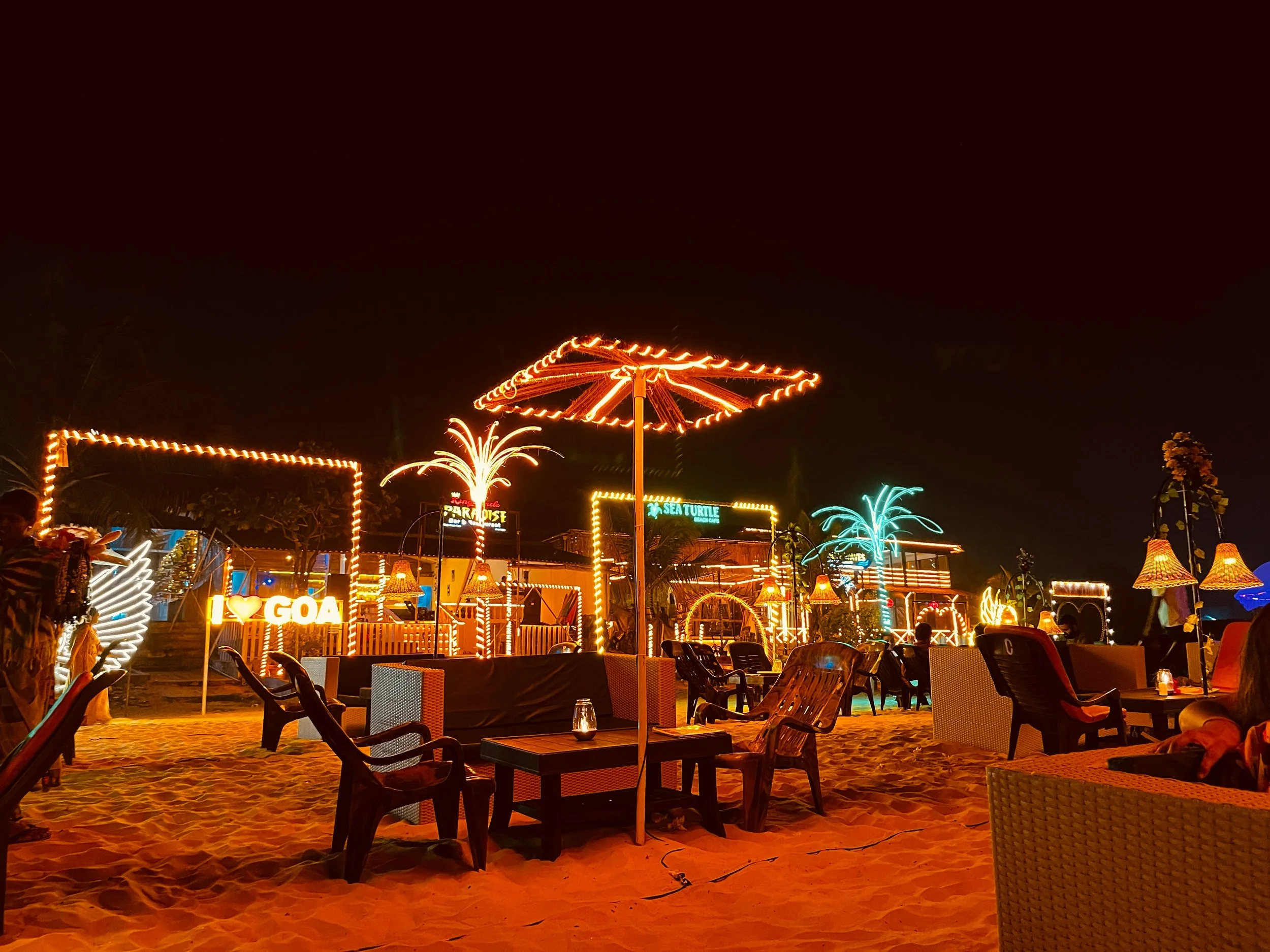 Fête d’entreprise de AYLO : un bar sur la plage de nuit avec lumières et palmiers, idéal pour des activités et soirées originales.