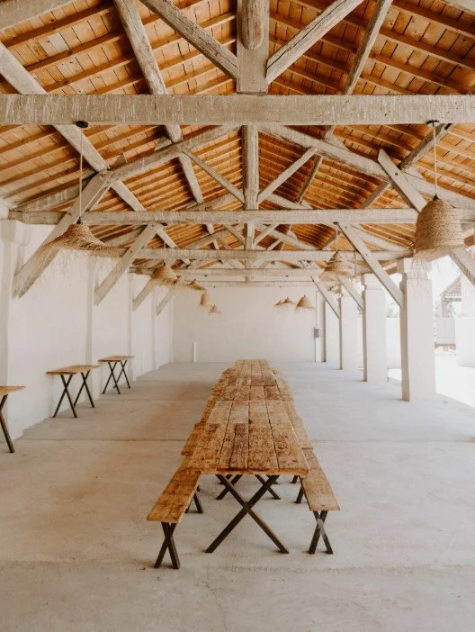 Salle de réception rustique au Domaine Le Sauvage avec une longue table en bois et des bancs, idéale pour les banquets ou séminaires d’Aylo Montagne.
