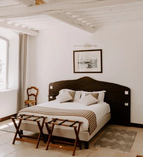 Chambre d’hôtel au Domaine Le Sauvage avec une tête de lit en bois sombre, dans un style rustique-chic, offrant un refuge calme et élégant dans la Camargue.