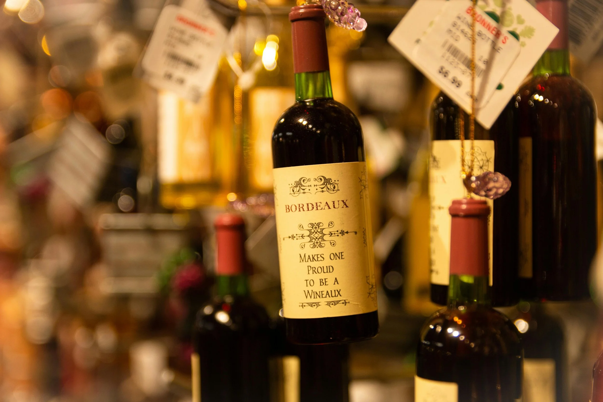Bouteille de vin rouge Bordeaux suspendue, avec son étiquette vintage centrée. La scène, chaleureusement éclairée, évoque une cave ou un magasin spécialisé dans les vins.