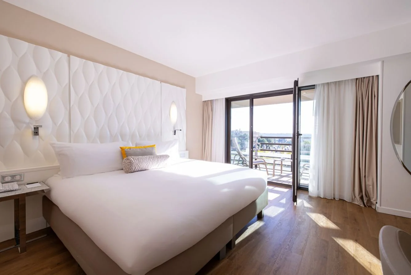 Chambre moderne et lumineuse à l’hôtel Renaissance Aix-en-Provence, avec balcon et lit King size.
