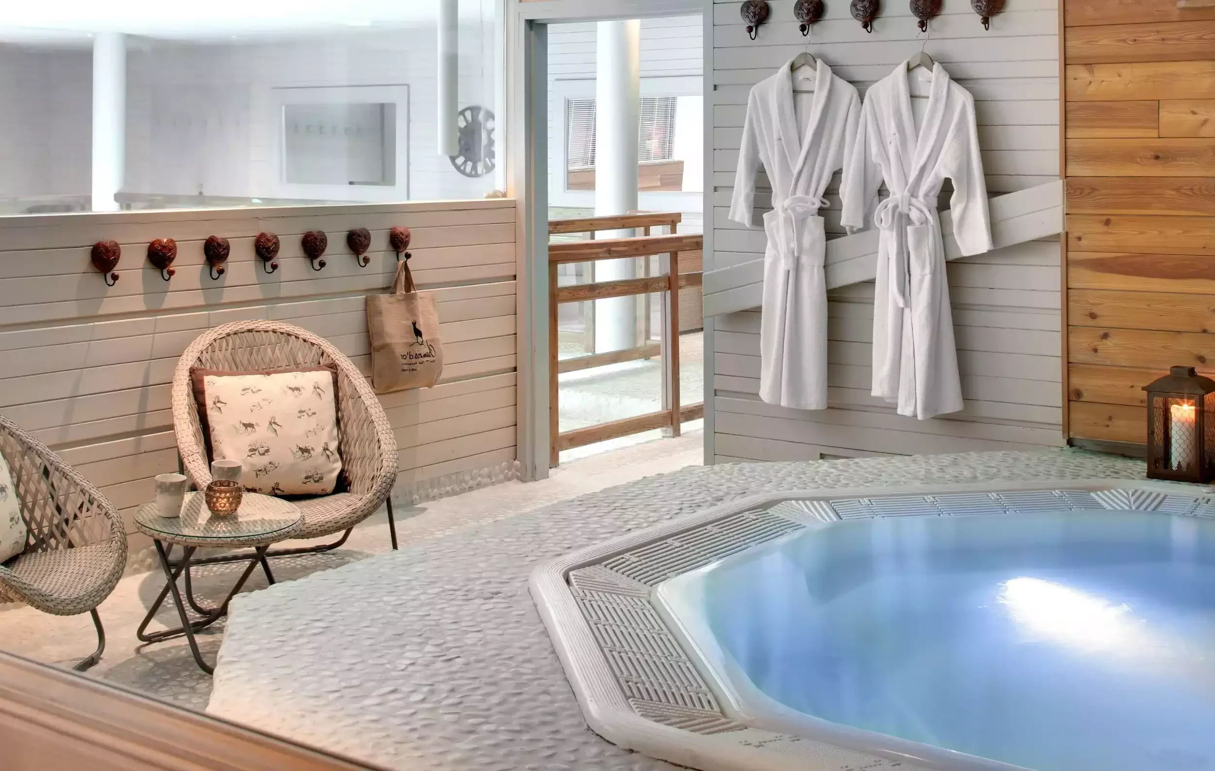 Espace spa extérieur de l'Hôtel Chamois d'Or 5* à L'Alpe d'Huez, avec jacuzzi, chaises et peignoirs blancs. Un lieu de détente luxueux pour les participants d'un séminaire Aylo Montagne.