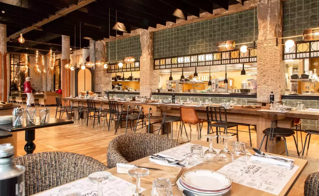 Intérieur du restaurant de l’Hôtel La Folie Douce 4*, avec de longues tables en bois préparées pour un banquet. Le style rustique-moderne est idéal pour les dîners de groupe ou des événements.