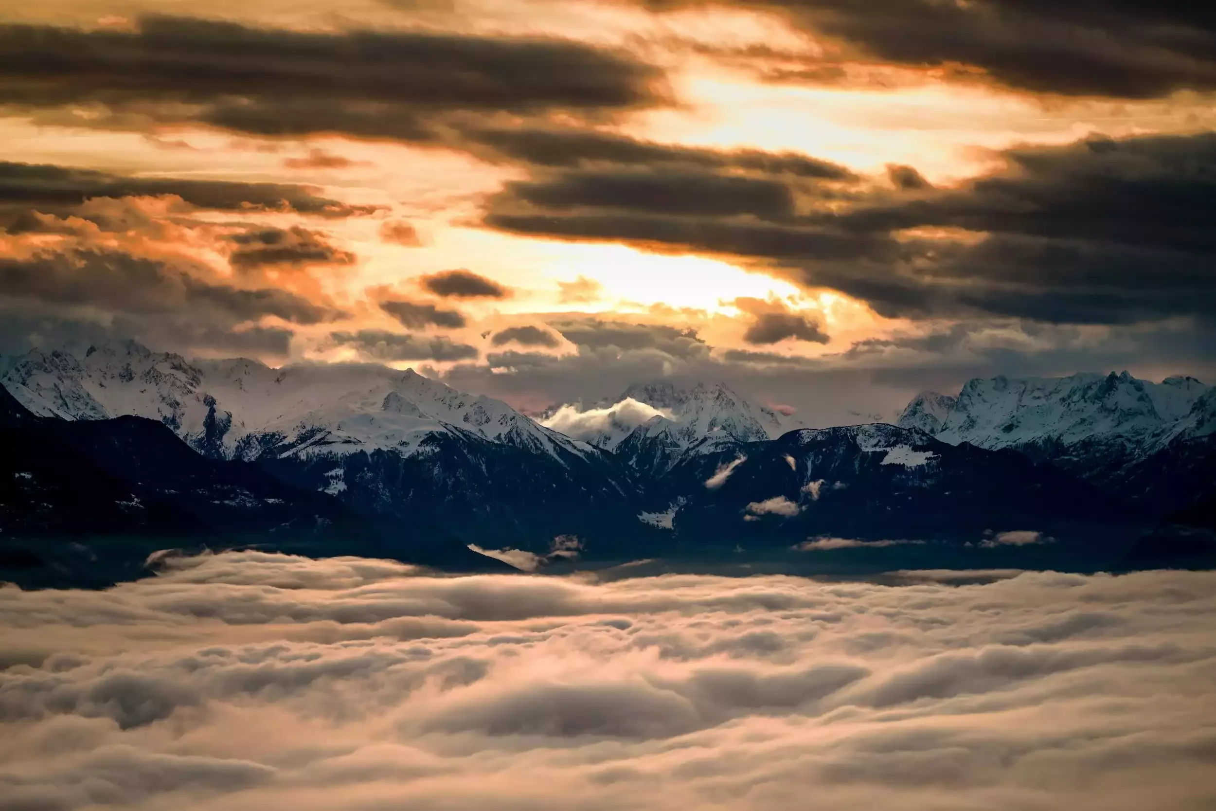 Majestueux paysage alpin à Crans-Montana au coucher du soleil, avec des sommets enneigés s’élevant sur une mer de nuages. Photo prise lors d’un séminaire avec Aylo montagne