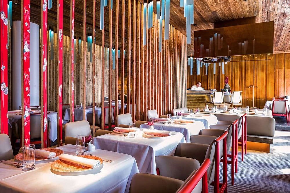 Restaurant design de l’hôtel The Alpina Gstaad, avec tables élégantes, bois naturel et ambiance gastronomique – Aylo Montagne.