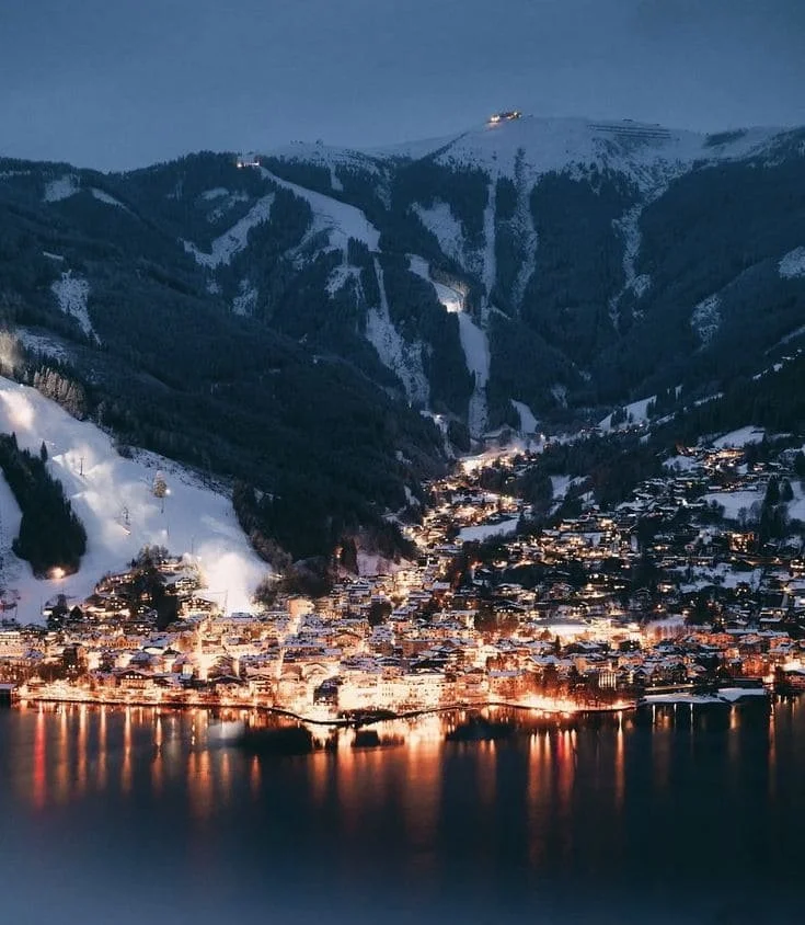 Vue nocturne de Kaprun en Autriche avec les montagnes enneigées et les lumières du village – destination séminaire d’entreprise Aylo Montagne.