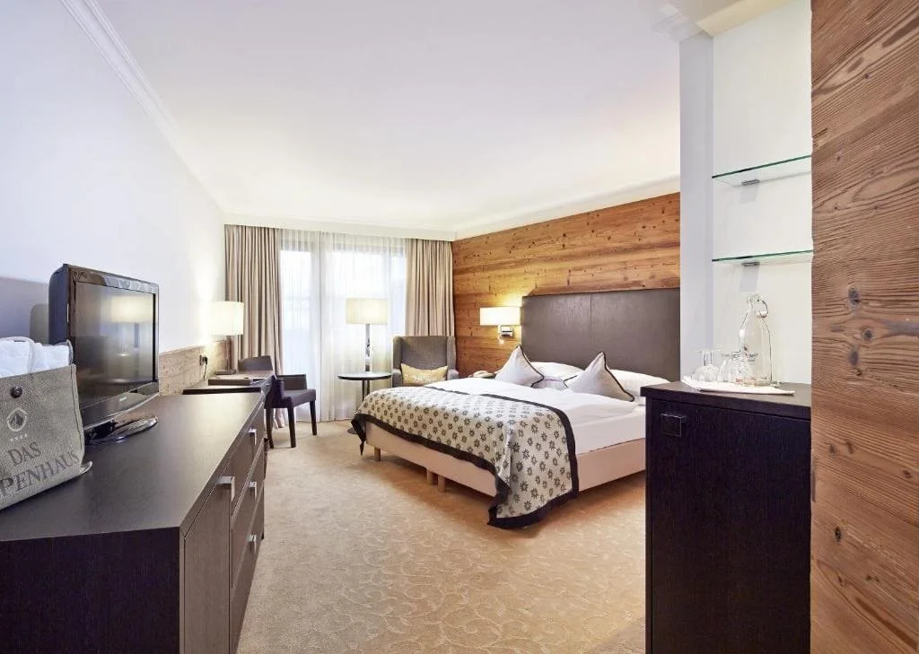 Chambre spacieuse et moderne de l’hôtel Alpenhaus Kaprun 4*, décoration alpine premium – hébergement haut de gamme pour séminaire à Kaprun avec Aylo Montagne.