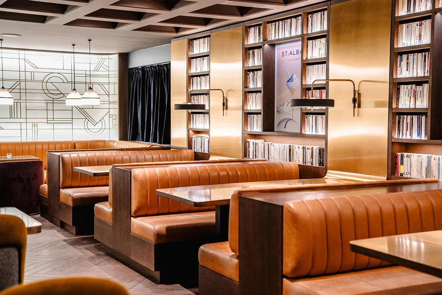 Restaurant de l’hôtel St. Alban avec un design rétro, des cabines en cuir et des murs avec des étagères pleines de livres, créant une atmosphère accueillante pour les repas.