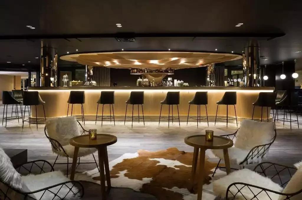 Bar au design moderne à l’hôtel L'Araucaria, avec un comptoir circulaire éclairé et des décorations en peau de vache, créant une atmosphère luxueuse.