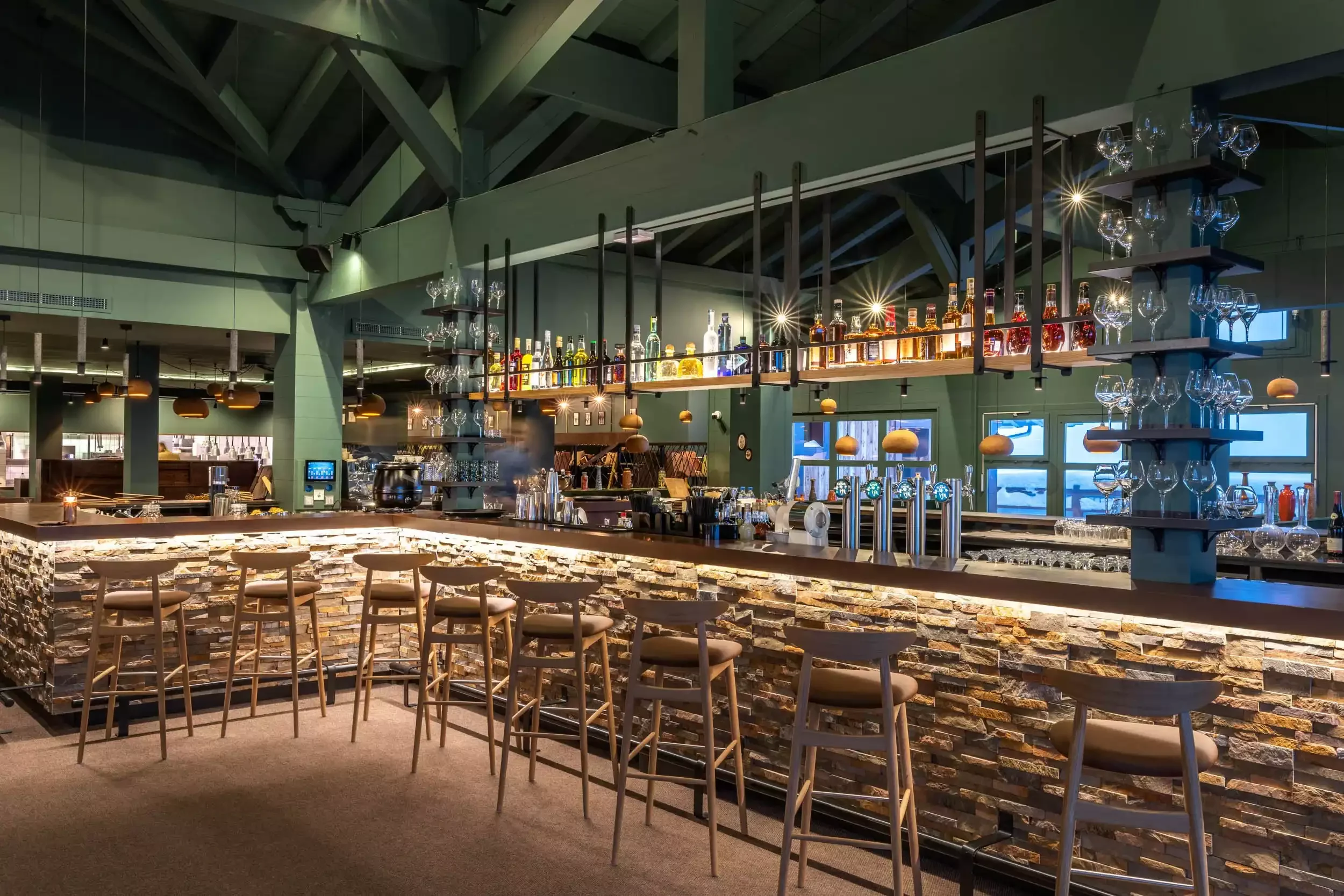 Bar design moderne à l’I.LY Hôtel, avec un comptoir en pierre et des chaises de style industriel. L’espace, avec son éclairage chaleureux, est idéal pour un cocktail.