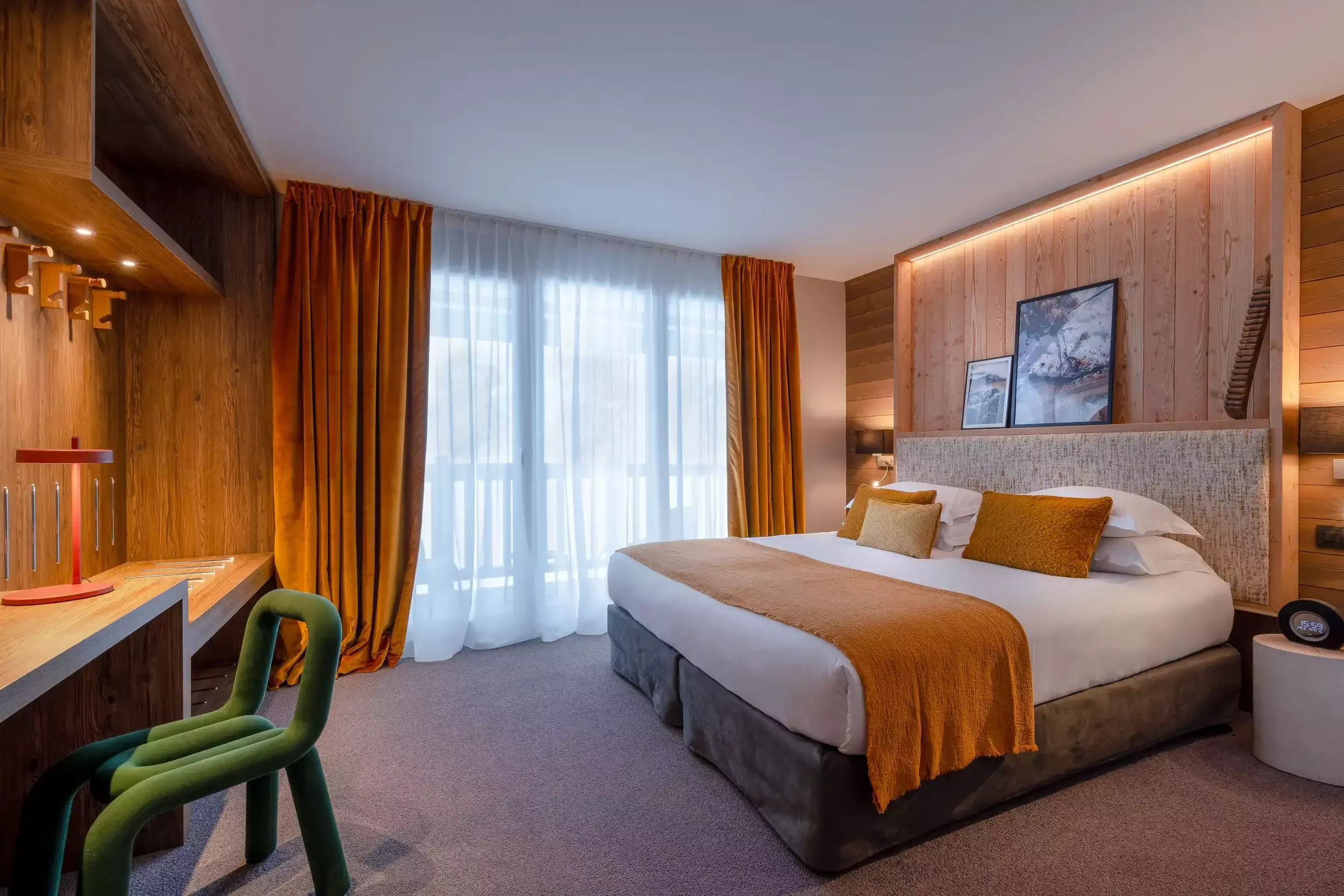 Chambre d’hôtel à l’I.LY Hotel avec un design moderne qui combine le bois et des tons chauds comme l’orange. La chambre offre un espace fonctionnel et accueillant pour les invités.