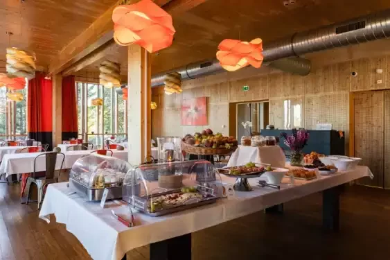 Restaurant de l’Aiguille Grive avec un buffet prêt à servir, entouré de murs en bois et des tables préparées pour les clients. L’espace est idéal pour les petits déjeuners et les déjeuners en groupe.