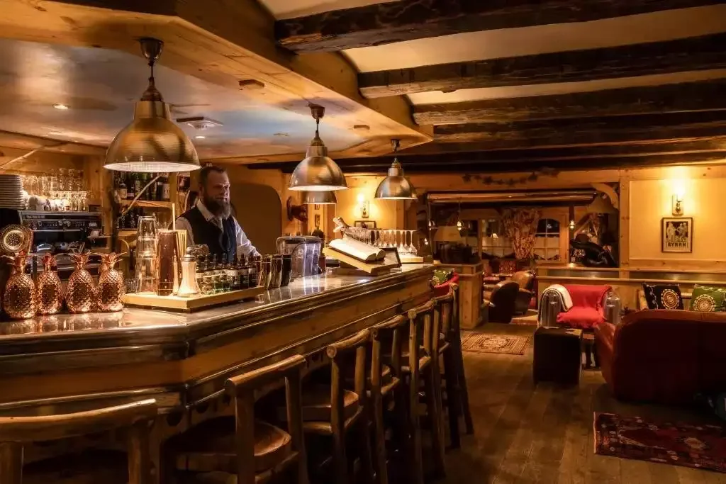 Bar de style rustique au Chalet Mounier, avec un comptoir en bois et un éclairage chaleureux, idéal pour se détendre et socialiser dans une ambiance traditionnelle après une journée de ski.