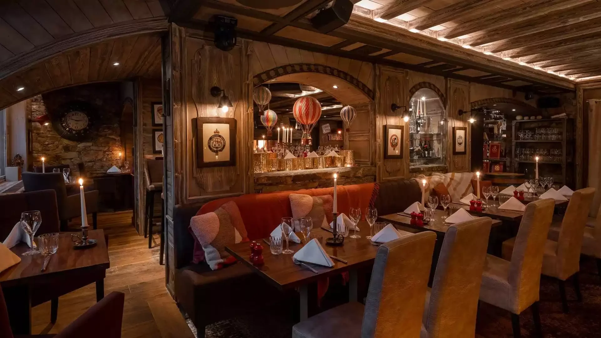 Intérieur du restaurant de La Chaudanne Hôtel à Méribel. L'espace a un design alpin chaleureux avec boiseries, banquettes rouges et éclairage tamisé, idéal pour les dîners de groupe d'un séminaire Aylo Montagne.