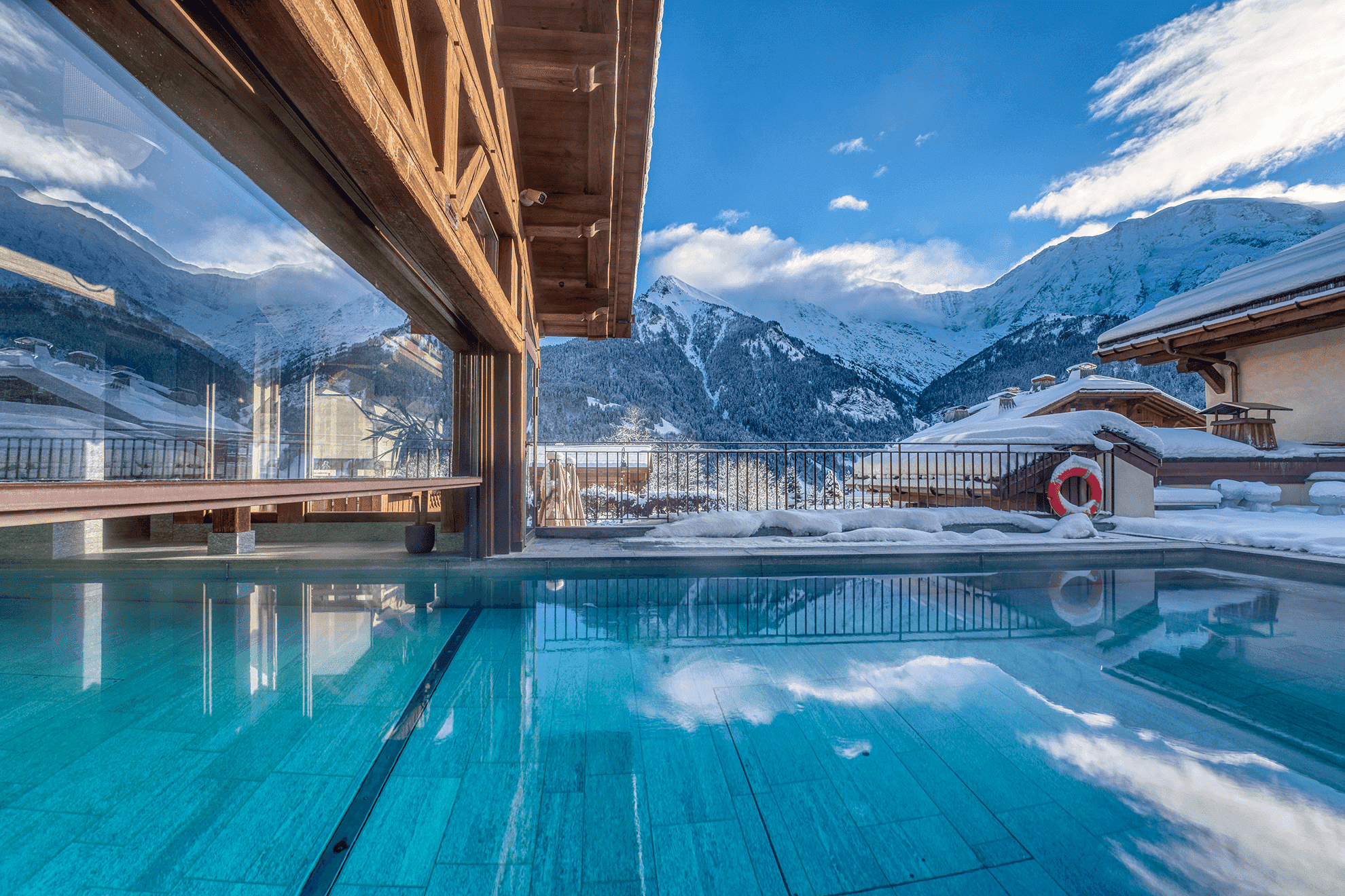 Piscine intérieure de l'Hôtel Armancette avec de grandes baies vitrées offrant une vue panoramique sur les montagnes enneigées. Un espace de luxe et détente pour les pauses d'un séminaire Aylo Montagne.