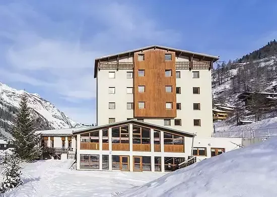 Vue extérieure de l’hôtel Club MMV Les Brévières 4* à Tignes. L’architecture combine des panneaux de bois avec une façade moderne, créant une atmosphère accueillante dans un environnement enneigé de montagne.