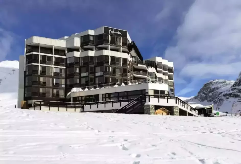 Façade de l’hôtel Belambra clubs, un grand bâtiment d’architecture moderne au pied des pistes. L’hôtel est situé sur une colline enneigée, avec vue sur les montagnes.