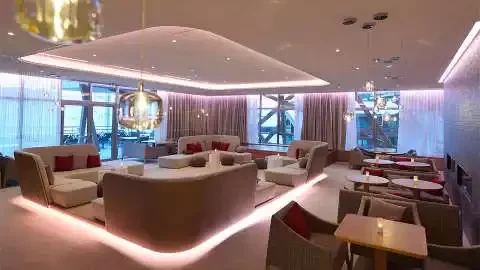 Salon d’hôtel de luxe au Club Med Val Thorens Sensations, avec des canapés design incurvé et un éclairage moderne, idéal pour se détendre avec vue panoramique sur la montagne.