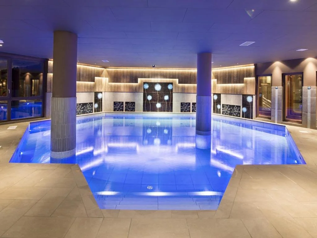 Piscine intérieure du Hameau du Kashmir avec éclairage bleu et un design moderne. L’espace est idéal pour la détente et le bien-être des clients, dans un cadre luxueux et paisible.