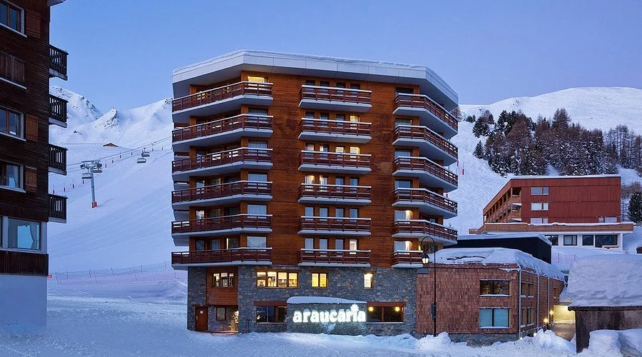 Façade de l’Hôtel L’Araucaria à La Plagne avec des participants rassemblés au pied de l’établissement pour un événement — idéal pour l’après-ski d’un séminaire Aylo Montagne.