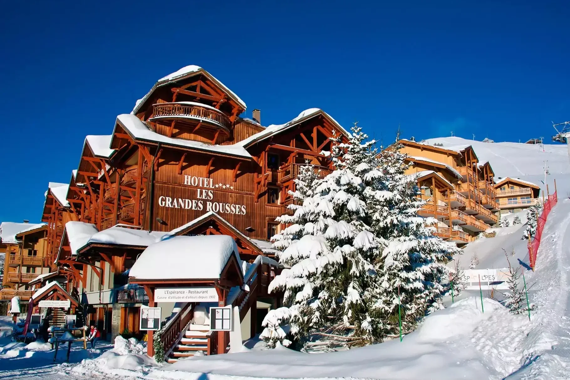 Façade majestueuse de l'Hôtel Grandes Rousses 5* à L'Alpe d'Huez, un grand chalet de bois directement au pied des pistes enneigées. Idéal pour un séminaire Aylo Montagne "ski-in/ski-out".