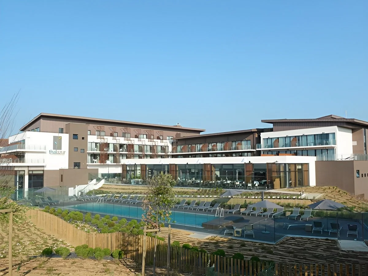 Façade extérieure moderne de l’Hôtel des Bains Thalazur à Cabourg. Le complexe à plusieurs étages s’élève sur une terrasse avec piscine, mettant en valeur son architecture contemporaine et sa proximité de la mer.