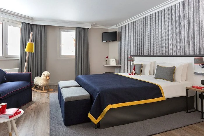 Chambre de L'Araucaria Hôtel avec un design moderne, murs à rayures grises et un lit fonctionnel. Parfait pour la pause d’un séminaire Aylo Montagne.