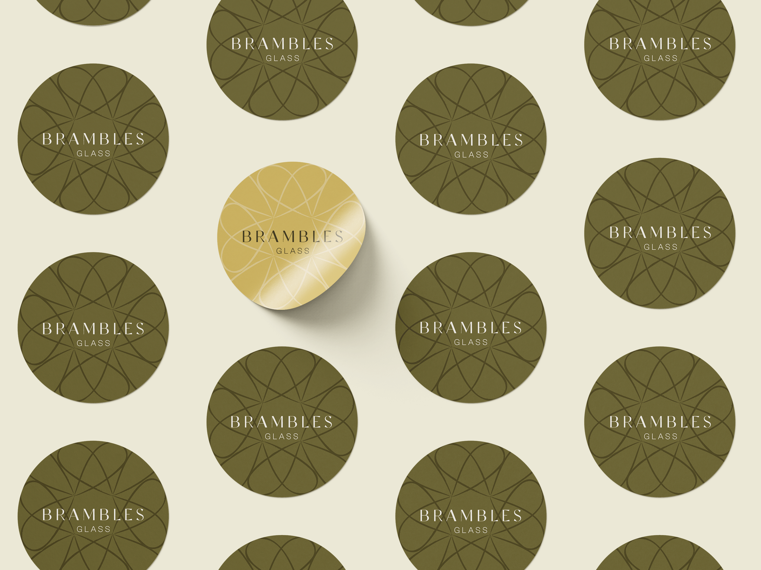 Multiple circular labels with a geometric pattern and the words "BRAMBLES GLASS" on a light background, with one gold label among many green labels.
