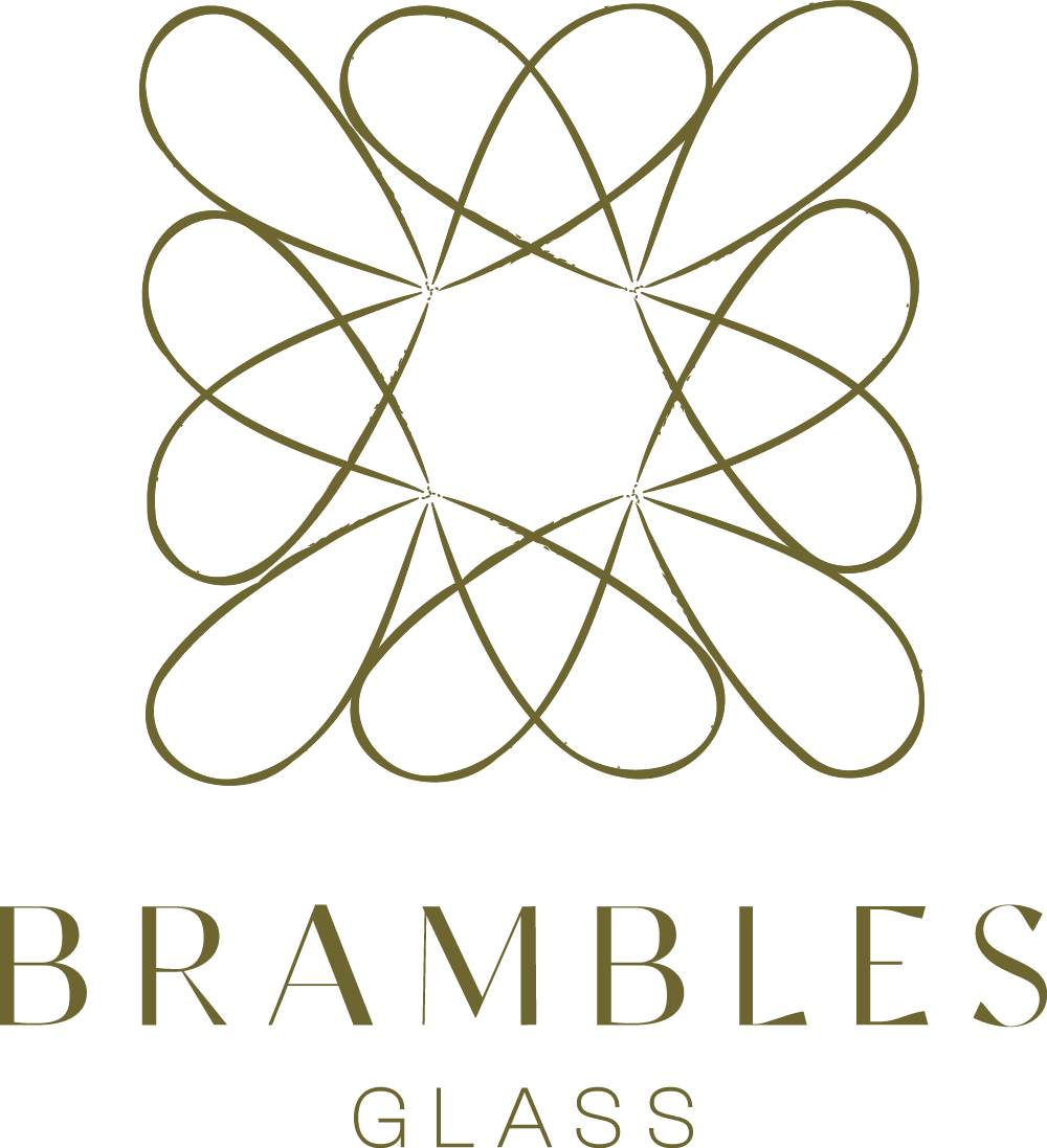 Logo for Brambles Glass featuring a symmetrical geometric design resembling intertwined loops with a central empty space, and the words "Brambles Glass" beneath it.