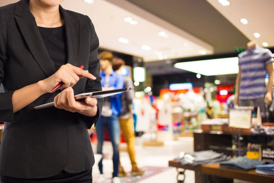 Une femme d'affaires dans un centre commercial utilisant une tablette ou un smartphone.