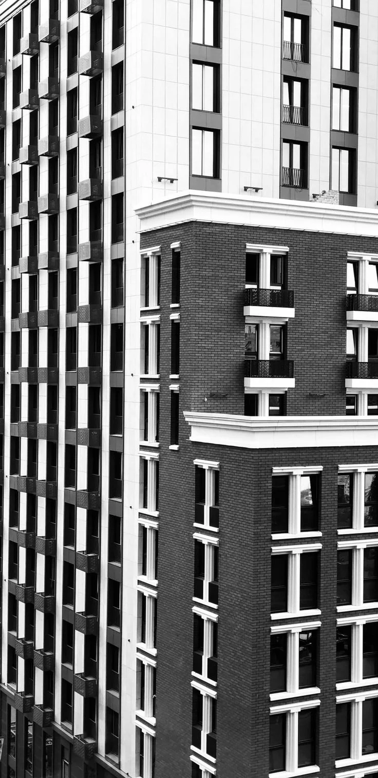 Black and white photo of high-rise apartment buildings with modern and traditional architectural elements, featuring numerous windows and small balconies.