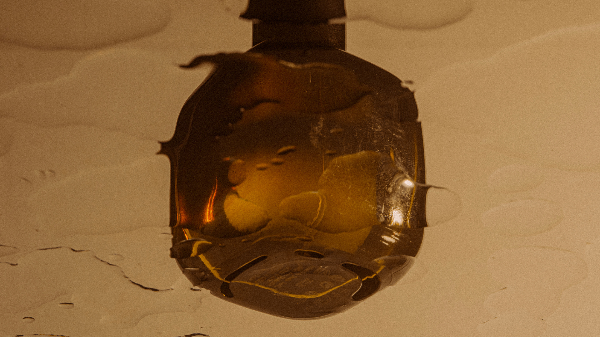 Close-up of a ceiling light fixture with a metal cover and exposed light bulb, reflecting part of the room in the shiny surface.