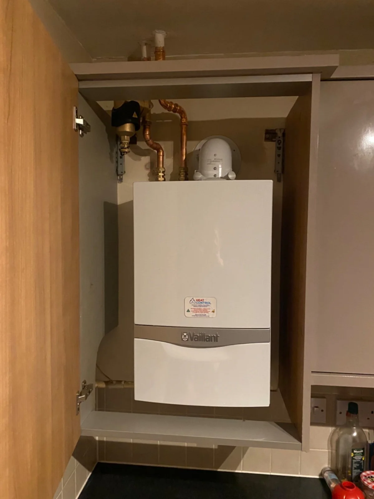 A boiler system installed inside a wooden cabinet in a utility room.