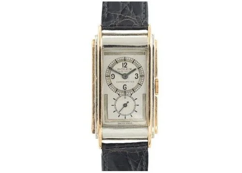 A rectangular gold and silver wristwatch with a black leather strap, featuring a dual-dial face and small subdials.
