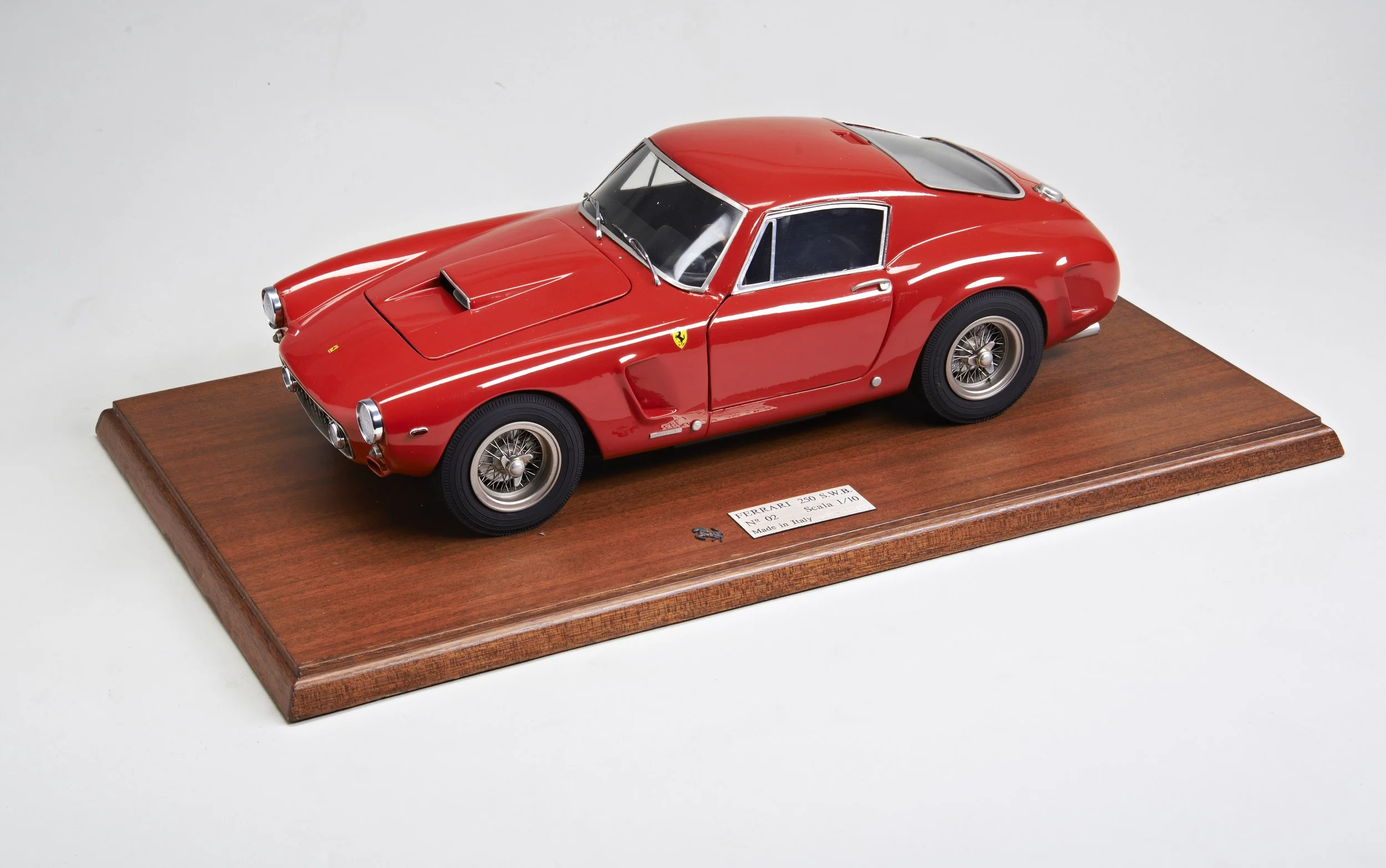 Scale model of a red Ferrari 250 GTO sports car on a wooden base.