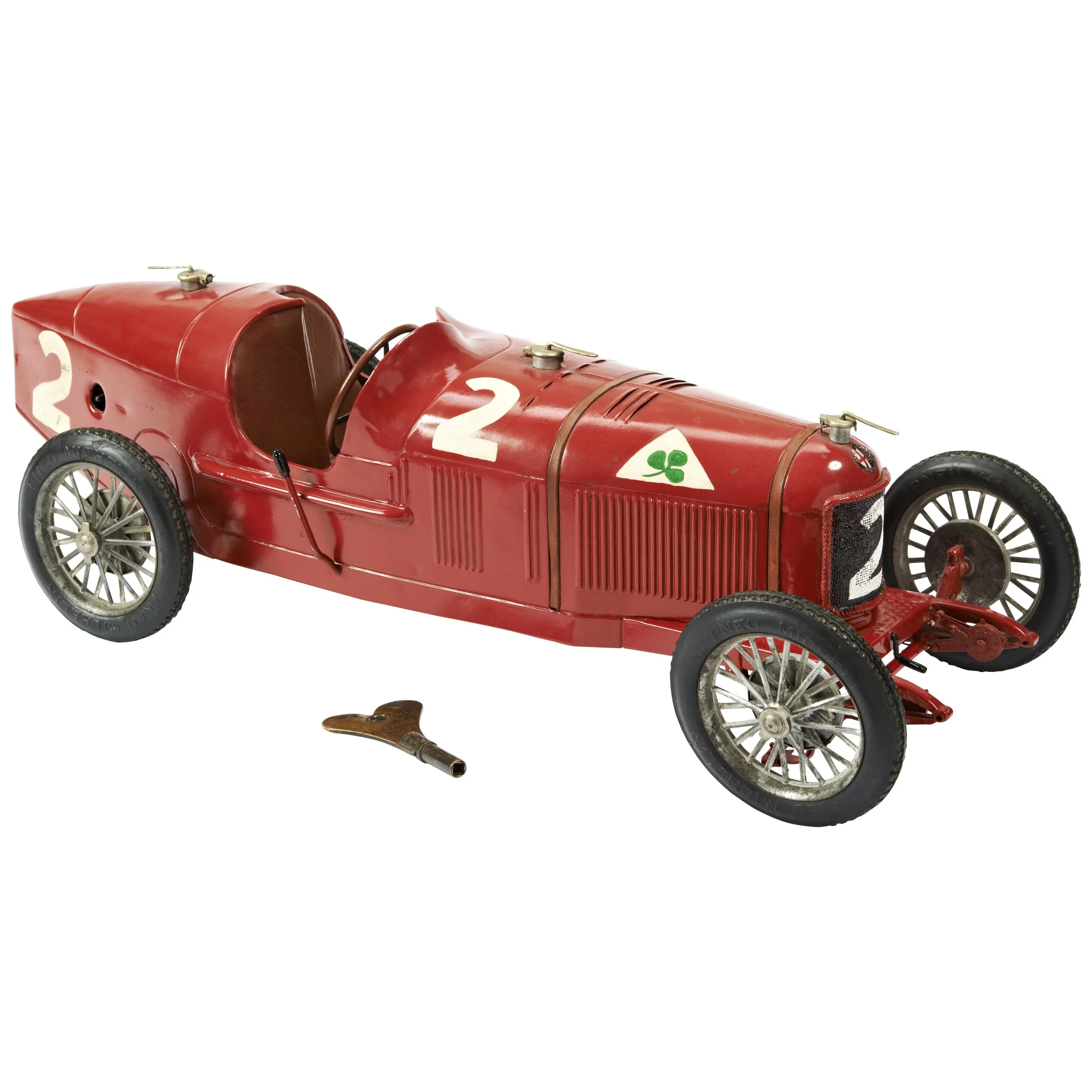 Vintage red race car with black tires, white number 2 on the side, and a small green shamrock decal, with a wrench nearby for maintenance.