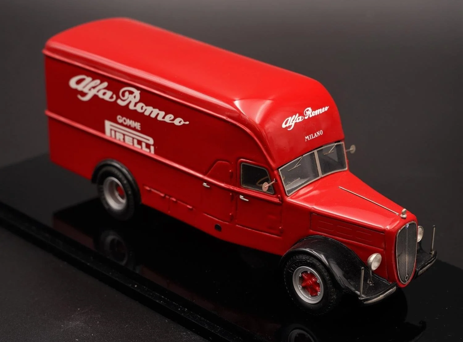 A red miniature model of an Alfa Romeo race car with sponsor logos including Pirelli, Como, and Milano, displayed on a black surface.