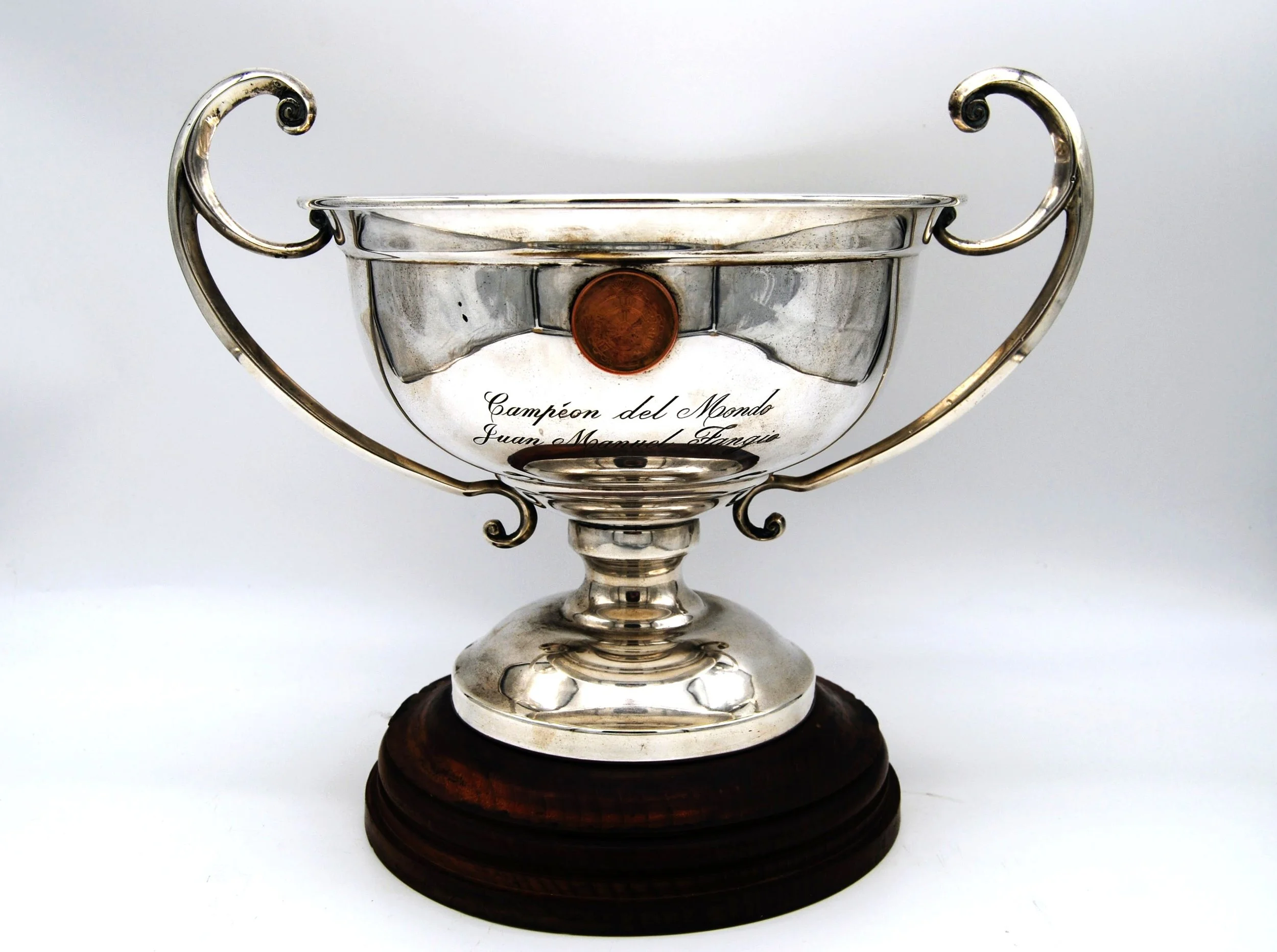 Close-up photograph of a bronze sculpture of a person driving a vintage car, showing their face and hands gripping the steering wheel.