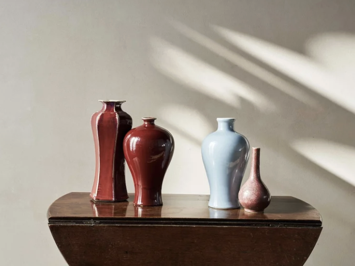 Four decorative vases with various shapes and colors displayed on a wooden table.