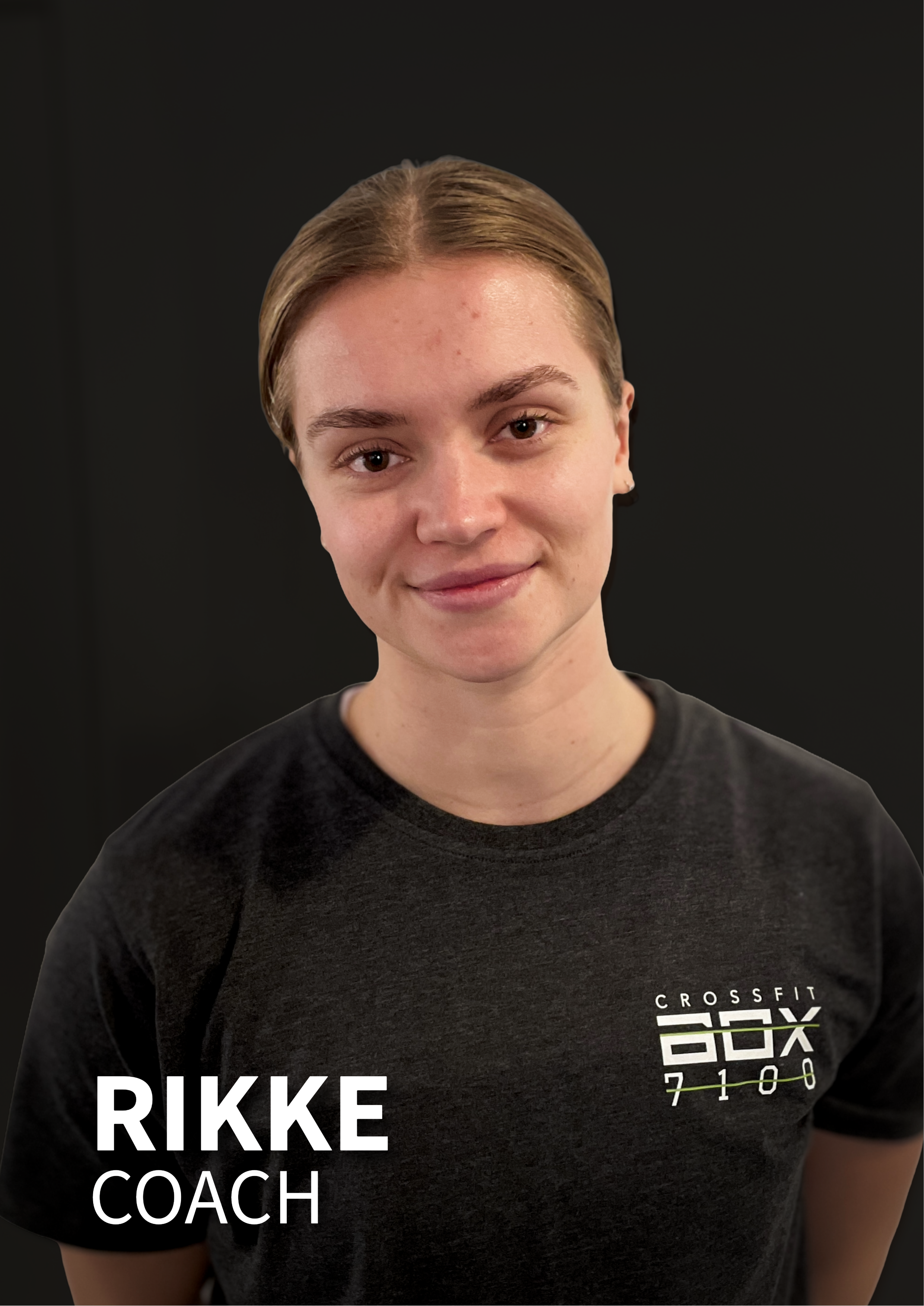 Person iført CrossFit T-shirt med teksten 'Rikke Coach' mod sort baggrund.