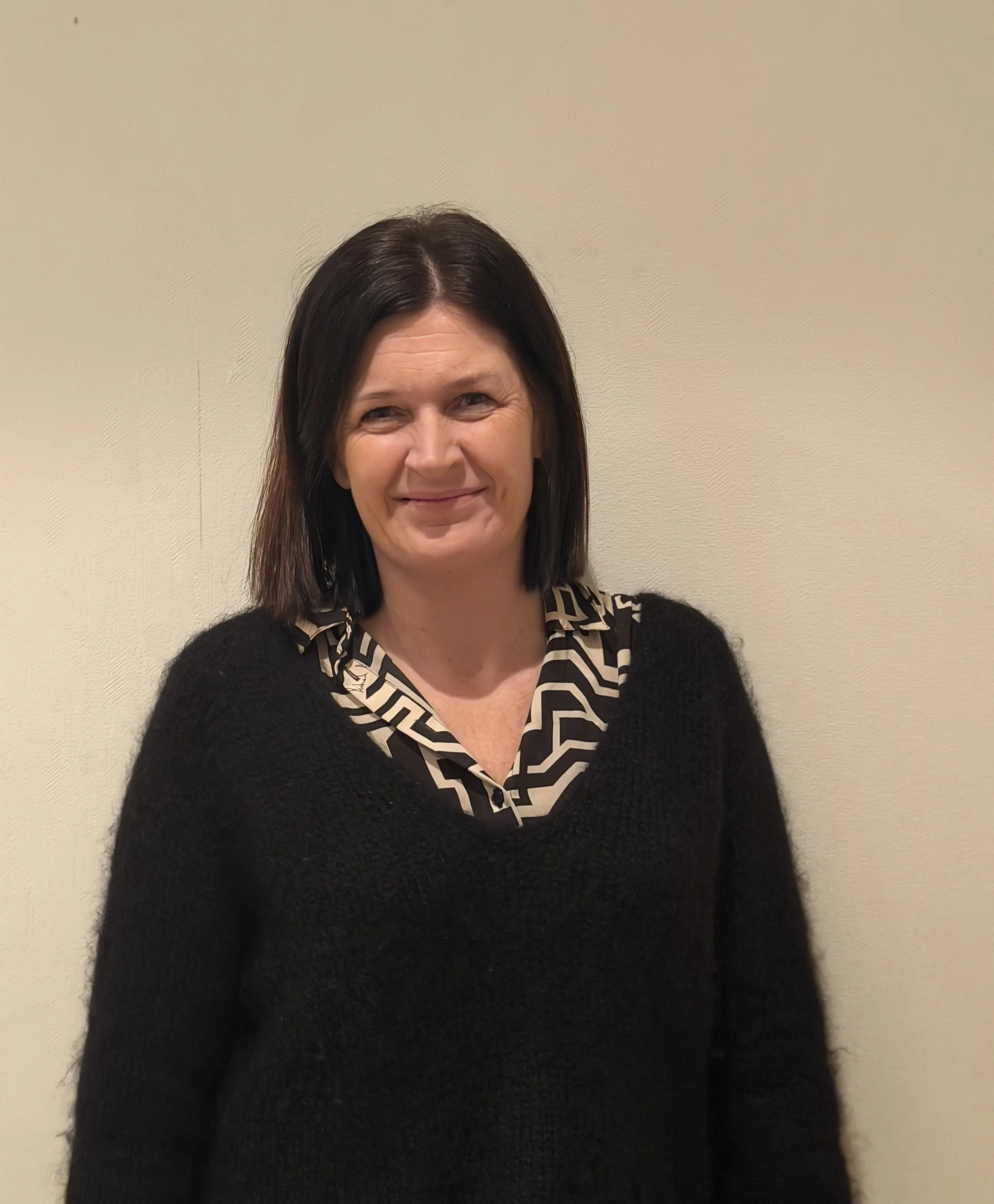 Fjell med snø, vann med refleksjon, og skyer i en klar himmel.