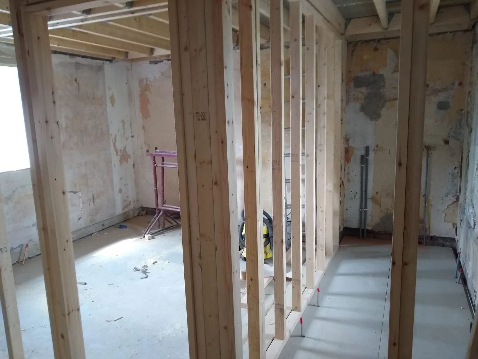 Interior of a building under construction with exposed wooden framing and unfinished walls.