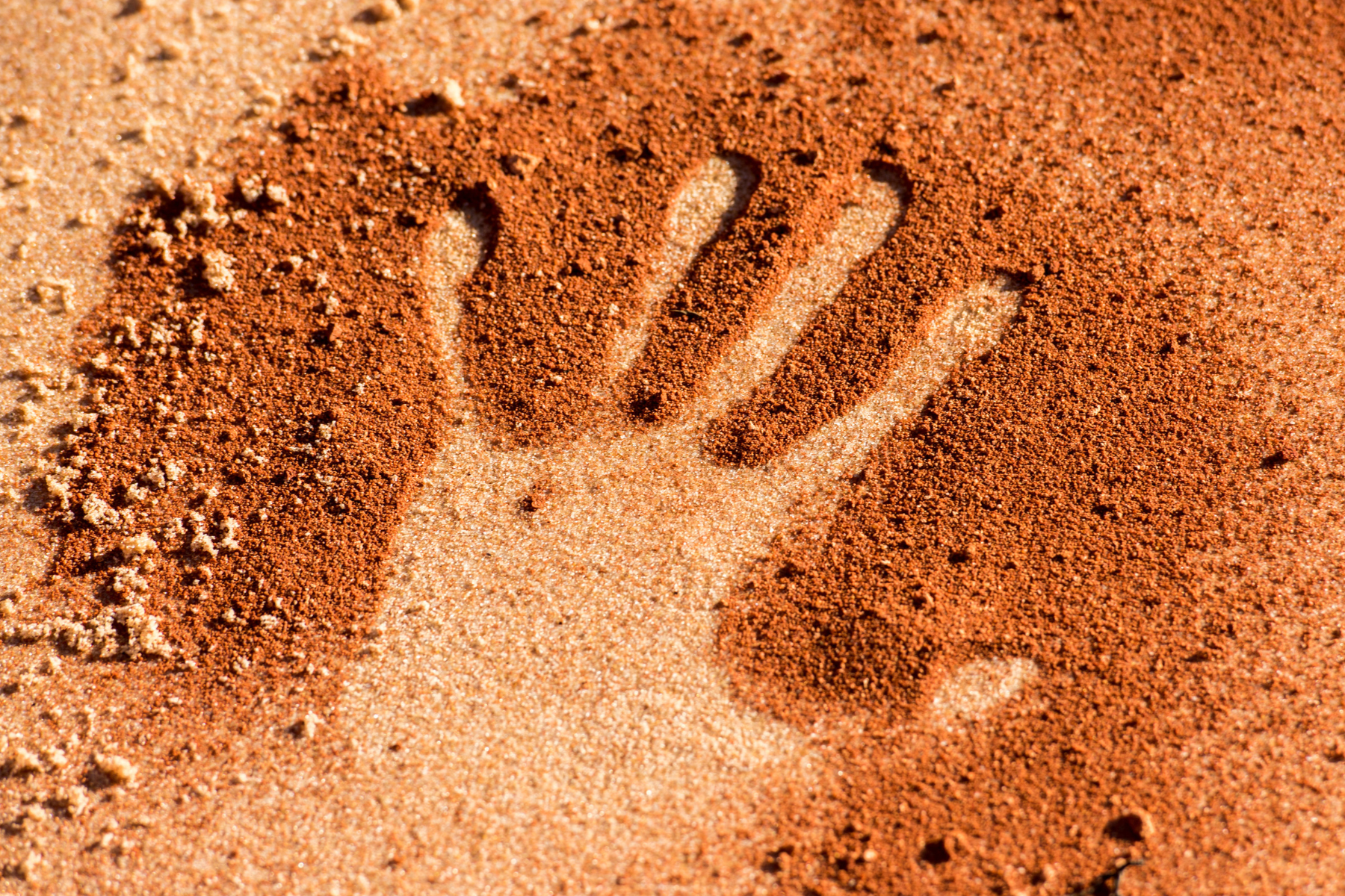 Outline of hand in red dirt