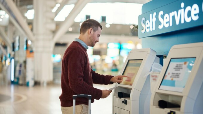 Man using a self-service kiosk at an airport.